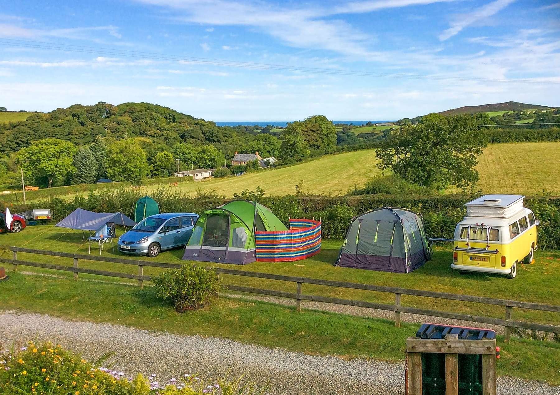 Tents, a campervan and a classic VW camper pitched in a row at Gwaun Vale
